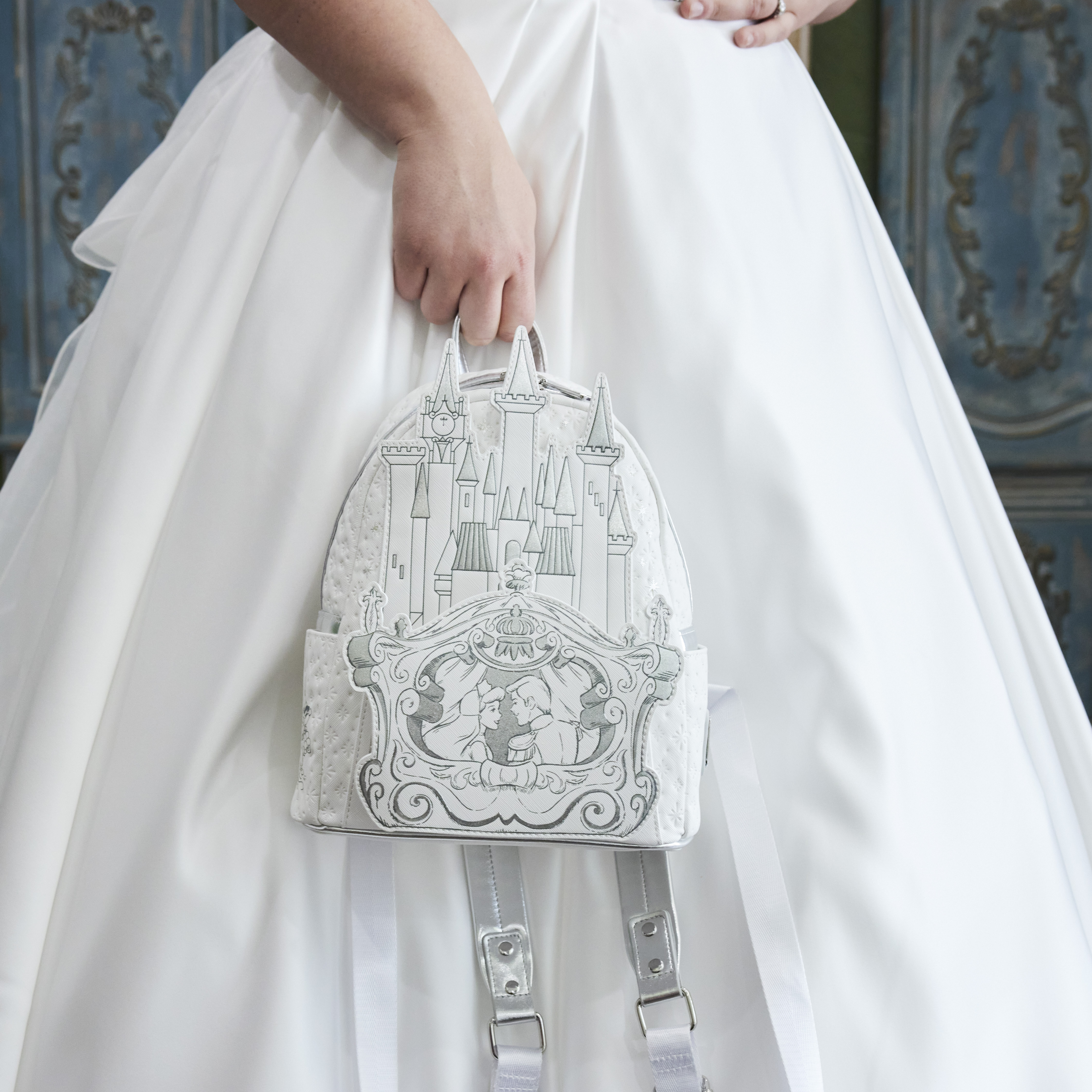 Close up shot of the Cinderella Happily Ever After Mini Backpack held against the skirt of a wedding dress
